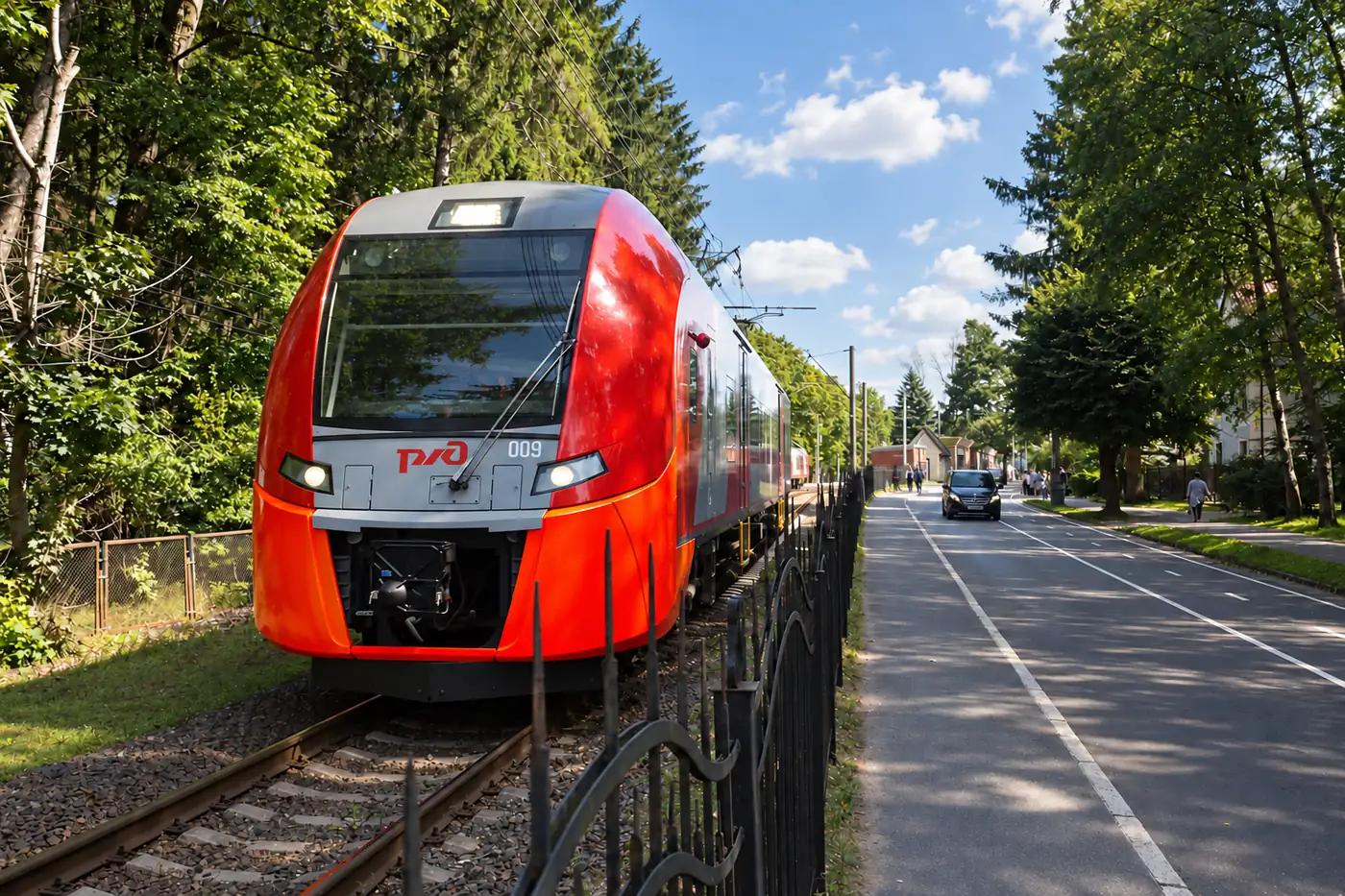Красно-серый электропоезд на железнодорожных путях рядом с дорогой